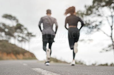 Buy stock photo Full length shot of two unrecognizable athletes bonding together during a run outdoors
