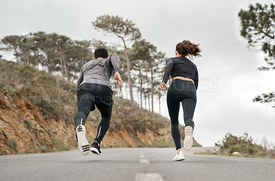 Buy stock photo Full length shot of two unrecognizable athletes bonding together during a run outdoors