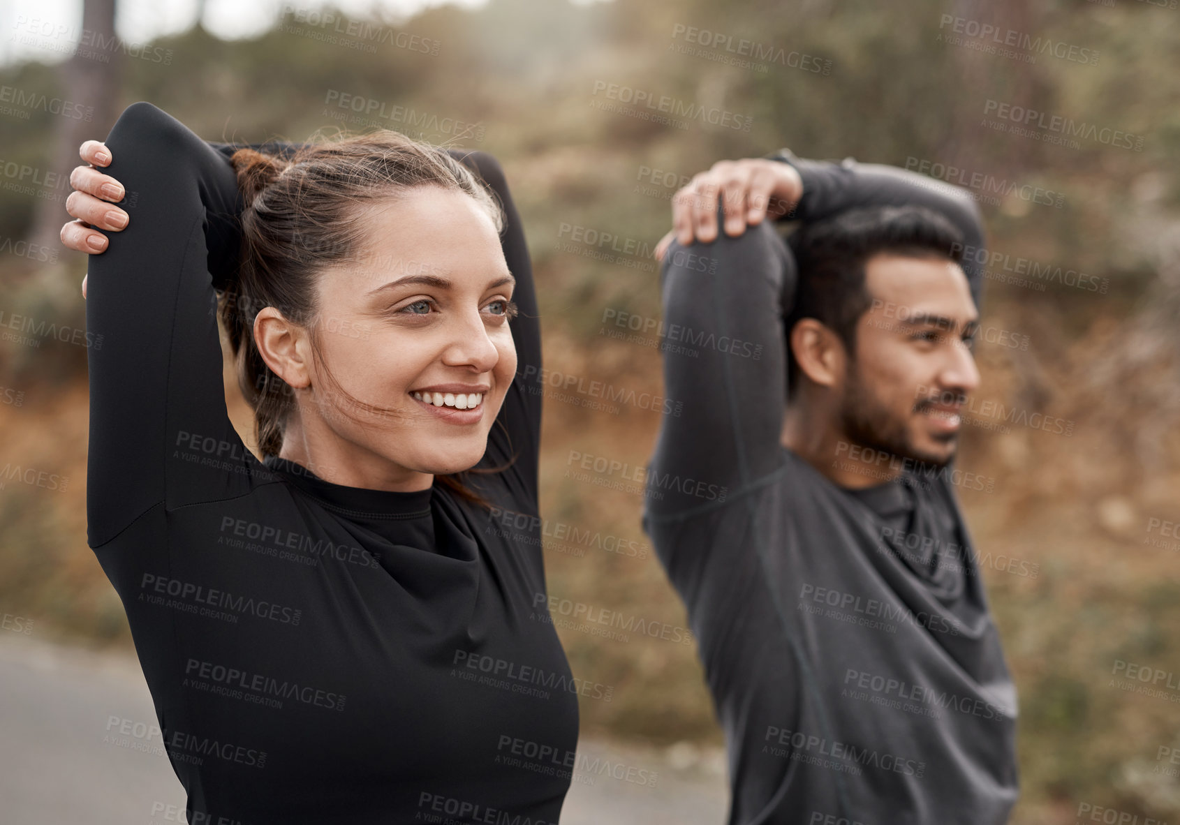 Buy stock photo Cropped shot of two young athletes stretching before exercising outdoors together