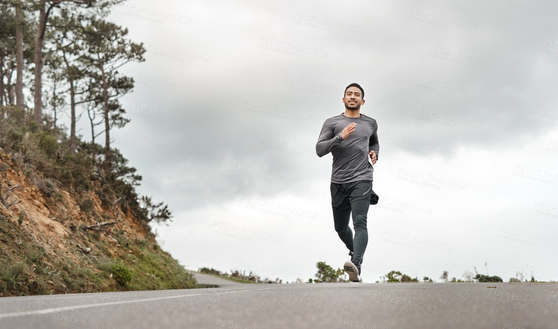 Buy stock photo Full length shot of a handsome young man jogging alone outdoors
