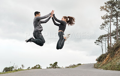 Buy stock photo Full length shot of two young athletes jumping for joy after their morning run outdoors