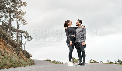 Buy stock photo Full length shot of two young athletes standing with their arms around each other after their morning run outdoors
