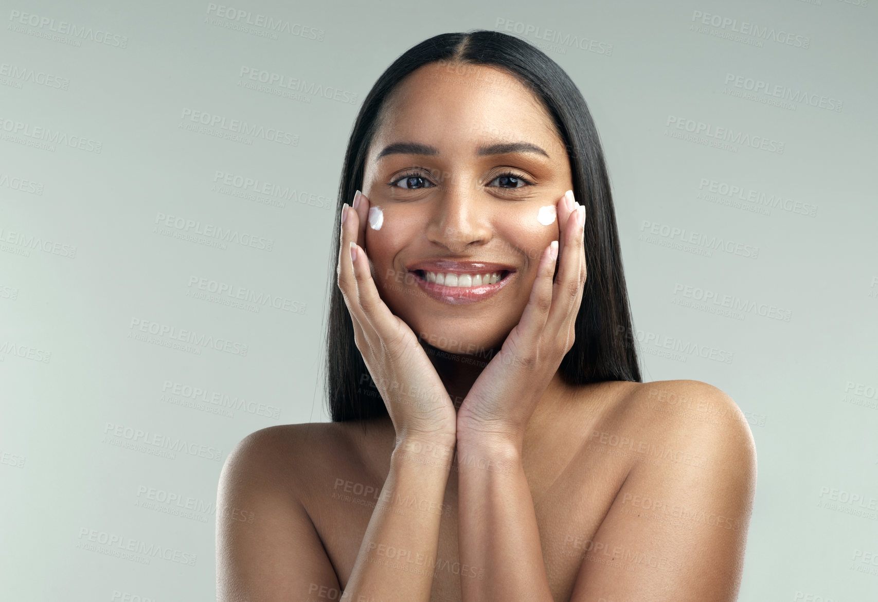 Buy stock photo Shot of a beautiful young woman applying moisturiser to her skin