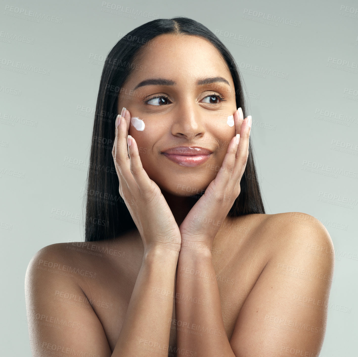 Buy stock photo Shot of a beautiful young woman applying moisturiser to her skin