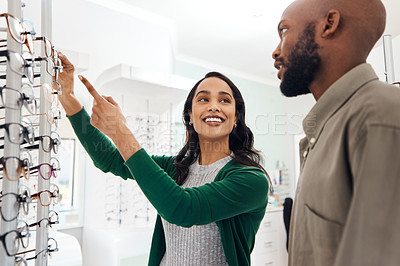 Buy stock photo Smiling optometrist assisting man with glasses in a modern sale optometry store. Attractive lady in customer service helping young, African and healthy male choose and buy eyewear in a shop.