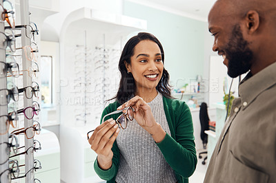 Buy stock photo Shot of a an optometrist helping a young man choose a new pair of glasses