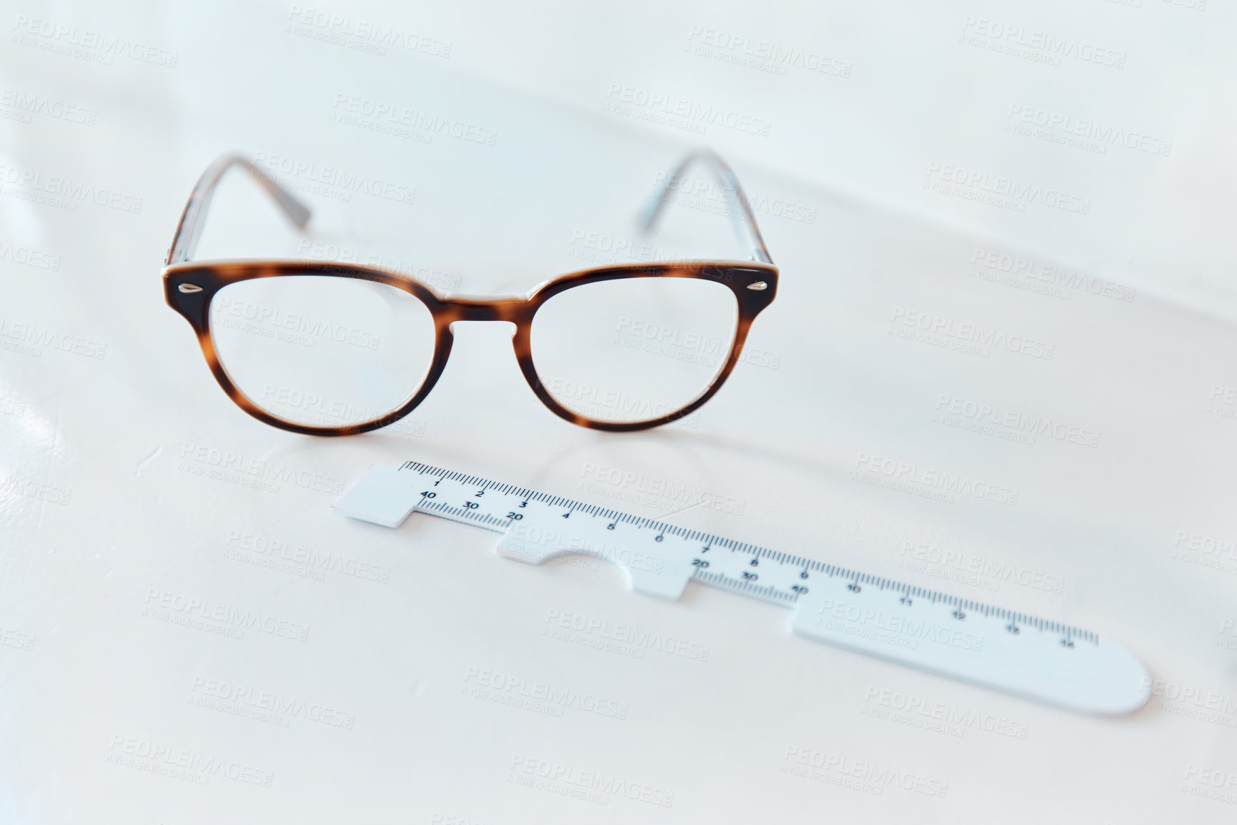 Buy stock photo Shot of a pair of glasses and a pd ruler in an optometrist’s office