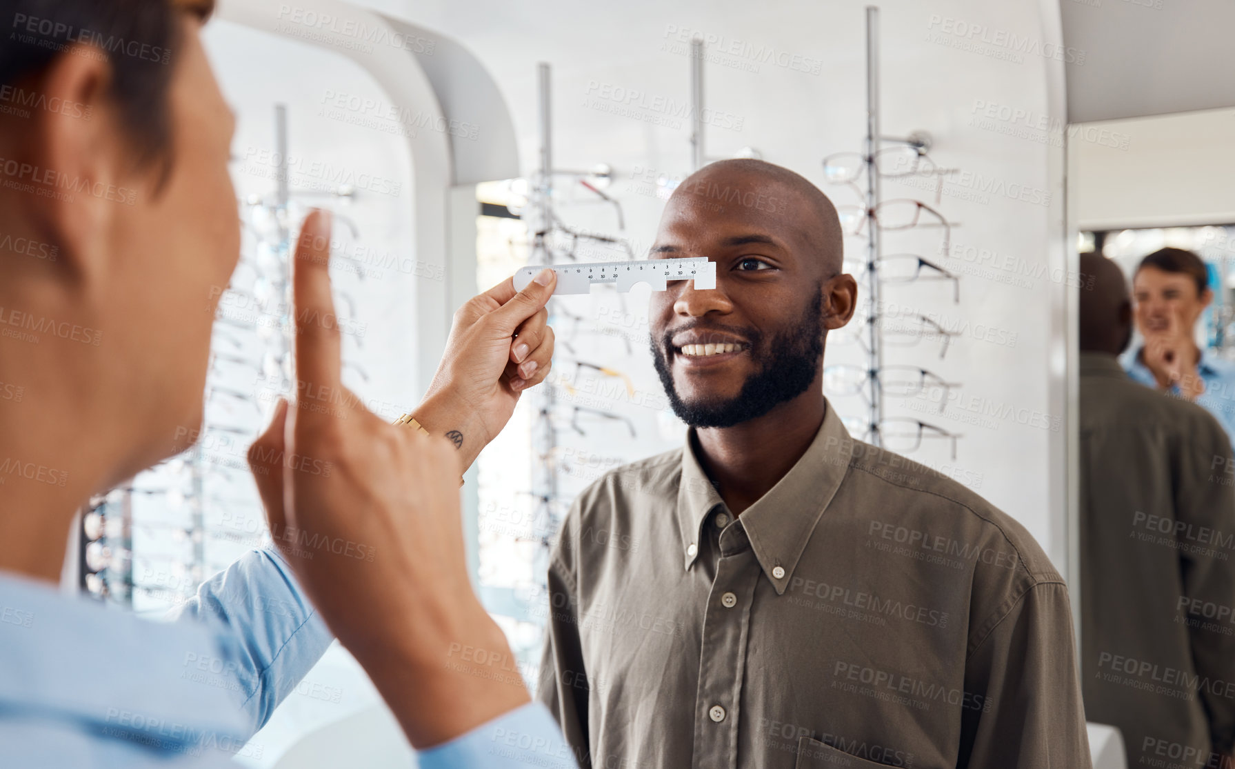 Buy stock photo Shot of an optometrist examining her patient’s eyes with a pd ruler