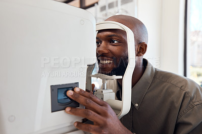 Buy stock photo Shot of a young man getting his eye’s examined with an autorefractor