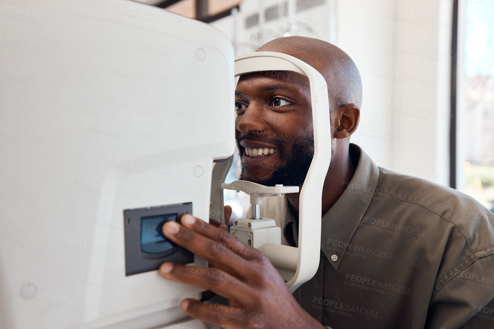 Buy stock photo Shot of a young man getting his eye’s examined with an autorefractor
