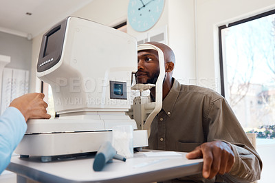 Buy stock photo Young African man getting an eye exam by an optometrist with technical optic equipment. Male getting an eyesight test with a autorefractor to get eyewear. Guy at an optical shop for new spectacles.