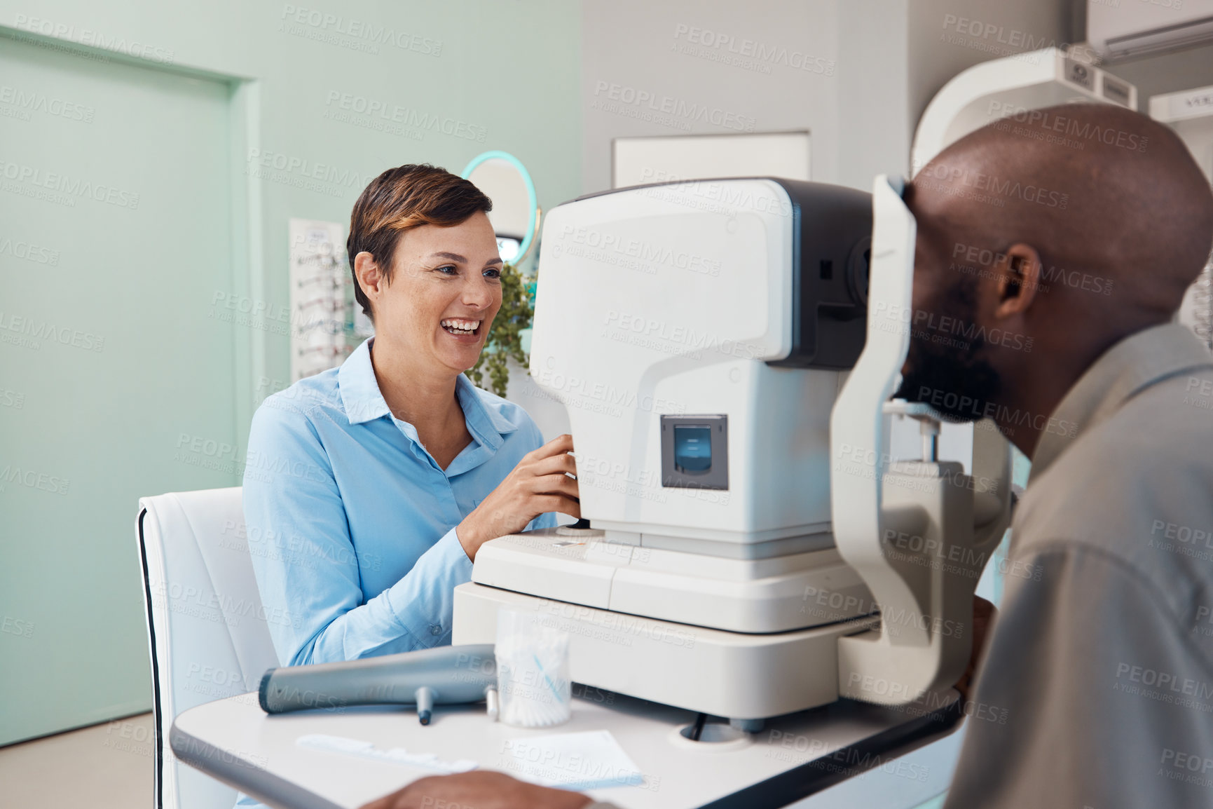 Buy stock photo Shot of an optometrist examining her patient’s eyes with an autorefractor