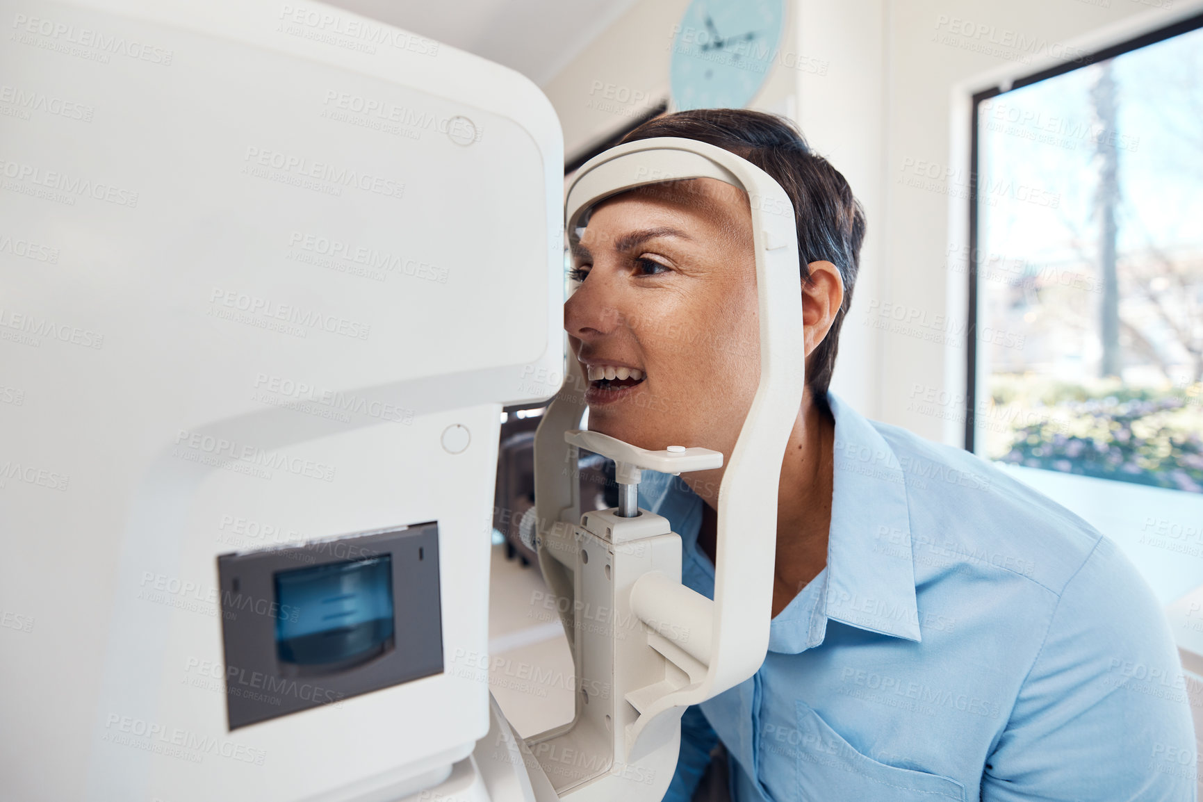 Buy stock photo An eye test, exam or screening for vision and eyesight at the optometrist or optician with a young woman. Testing her sight with an automated refractor for prescription glasses or contact lenses
