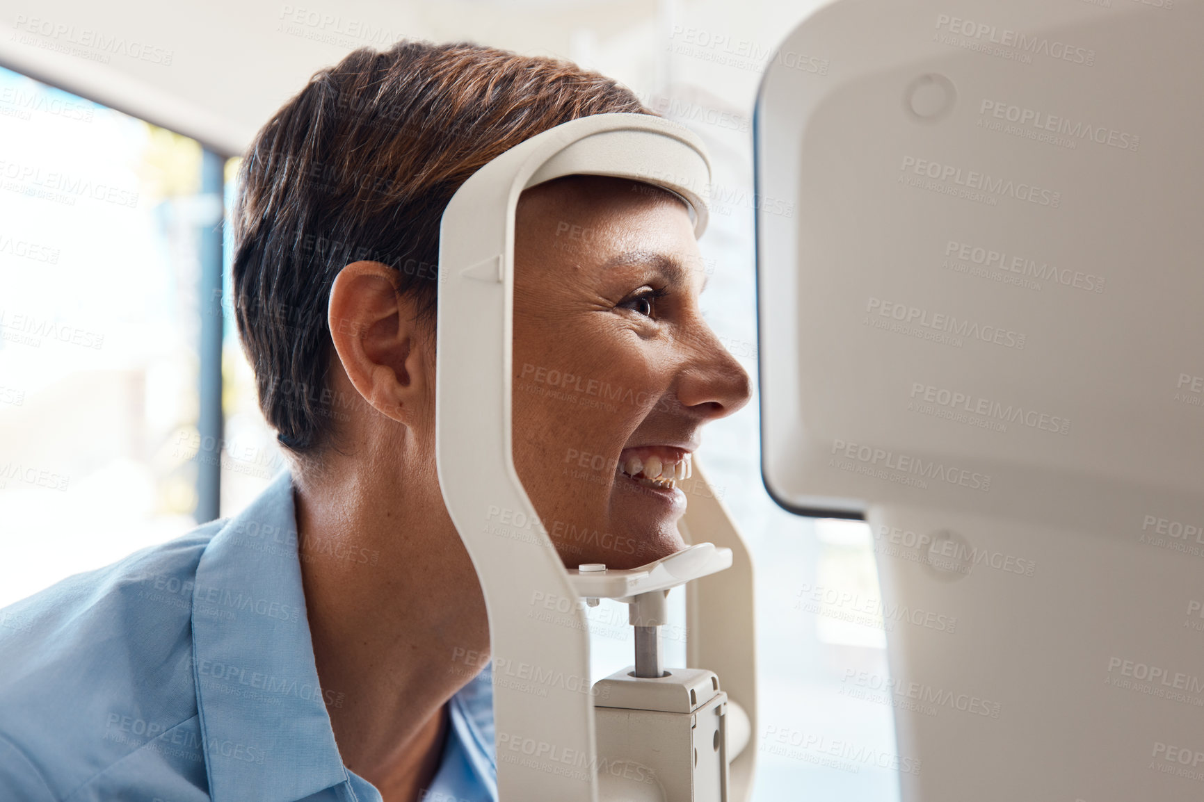 Buy stock photo Shot of a young woman getting her eye’s examined with an autorefractor