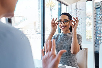 Buy stock photo A customer buying, testing or trying on glasses at an optometrist store or shop. Health care eye wear professional picking or selling a pair of new eyeglasses to a young female client or patient.