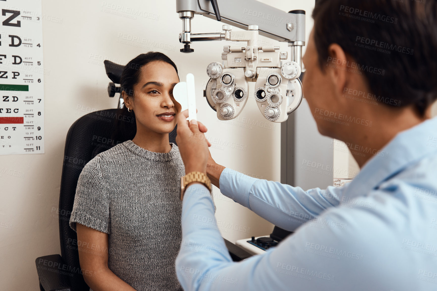 Buy stock photo Shot of an optometrist covering her patient’s eyes with an occluder during an eye exam