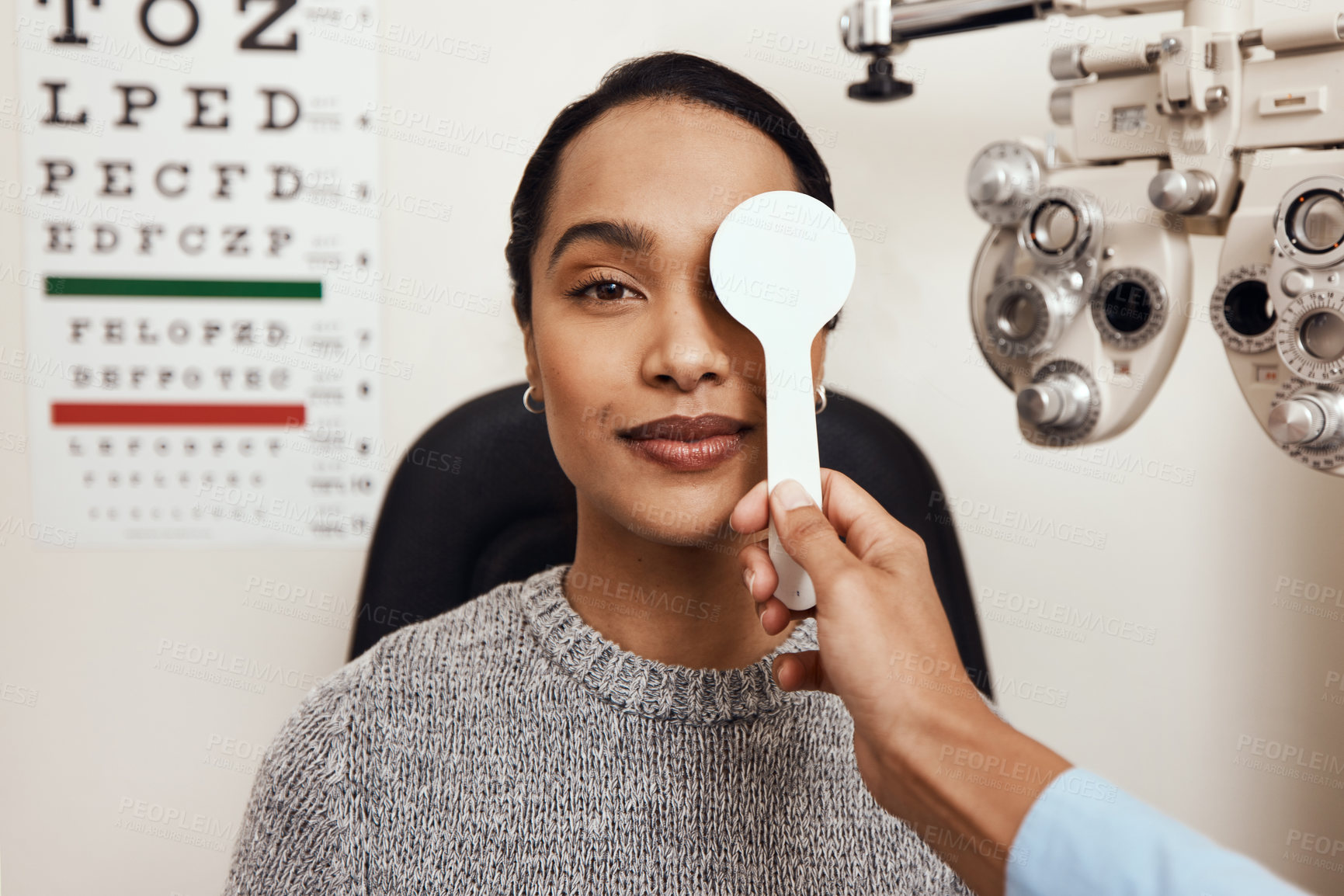 Buy stock photo Shot of an optometrist covering her patient’s eyes with an occluder during an eye exam