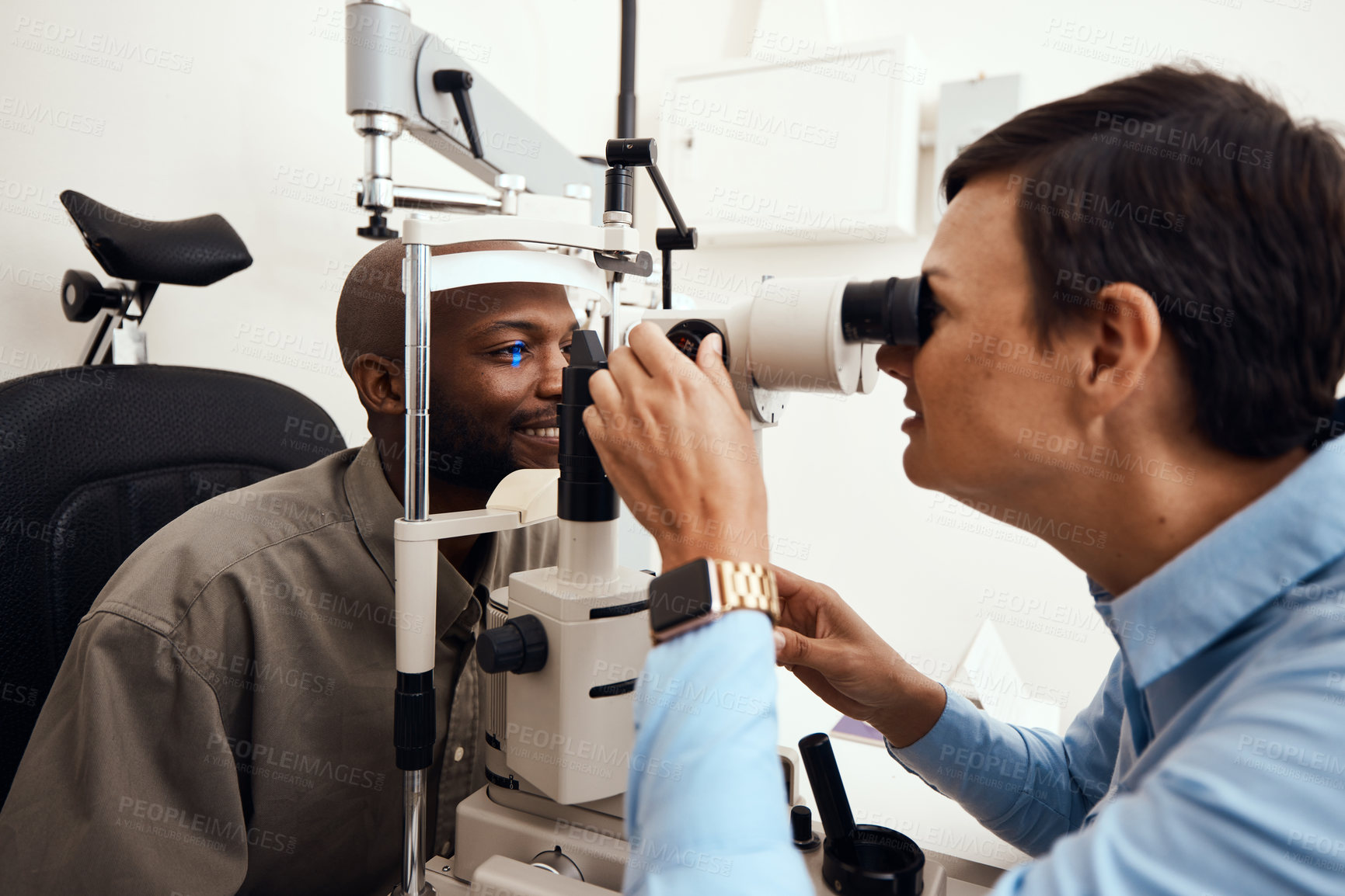 Buy stock photo Shot of a young man getting his eye’s examined with a slit lamp by an optometrist