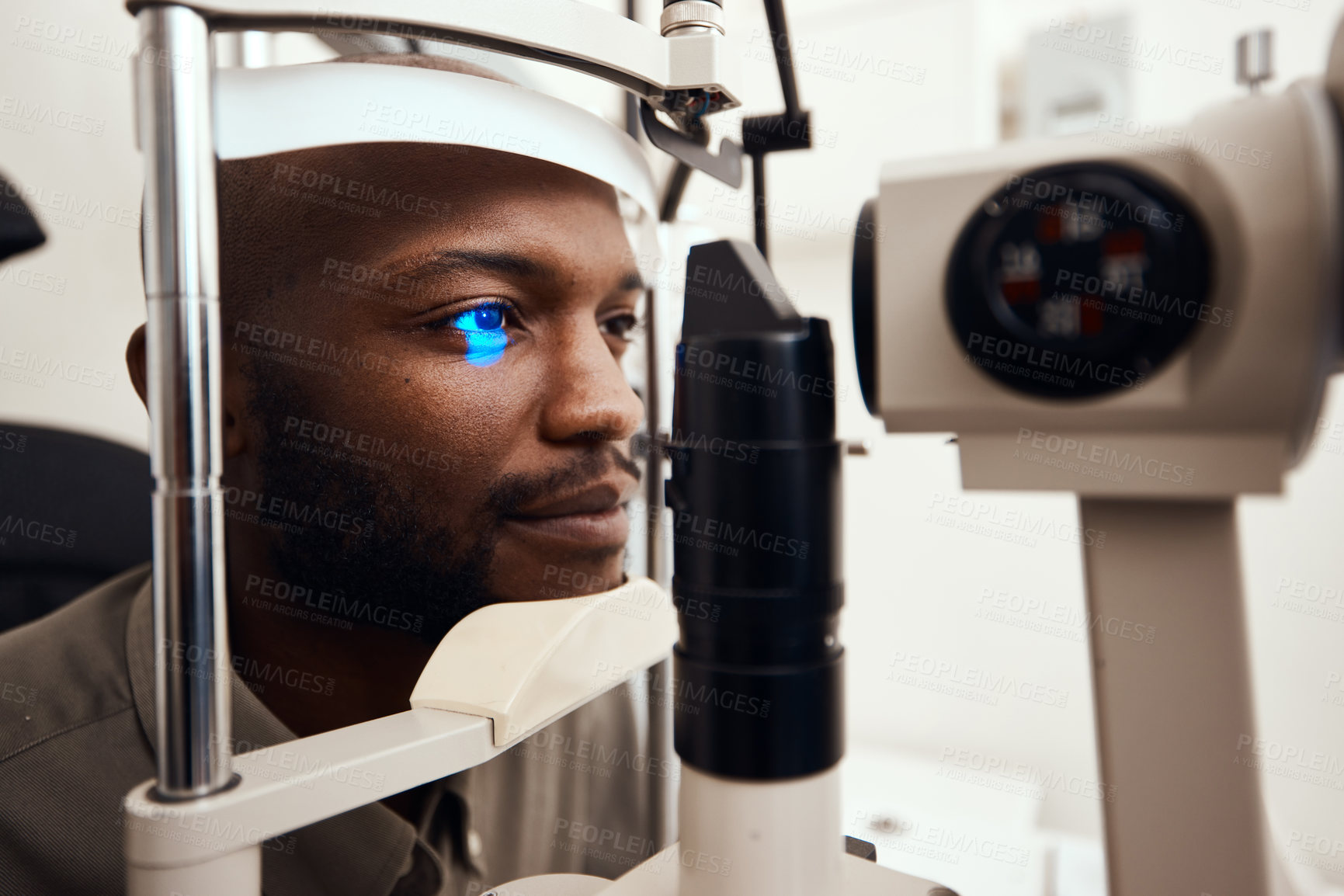 Buy stock photo Shot of a young man getting his eye’s examined with a slit lamp
