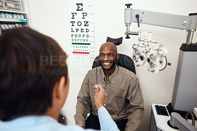Buy stock photo Shot of a young man having an eye test conducted by an optometrist