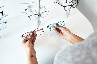 Buy stock photo Buying, looking and shopping for glasses at a retail eyewear store and optometrist inside. Customer holding shop stock trying to decide on a new modern style, trendy and stylish frames to buy on sale