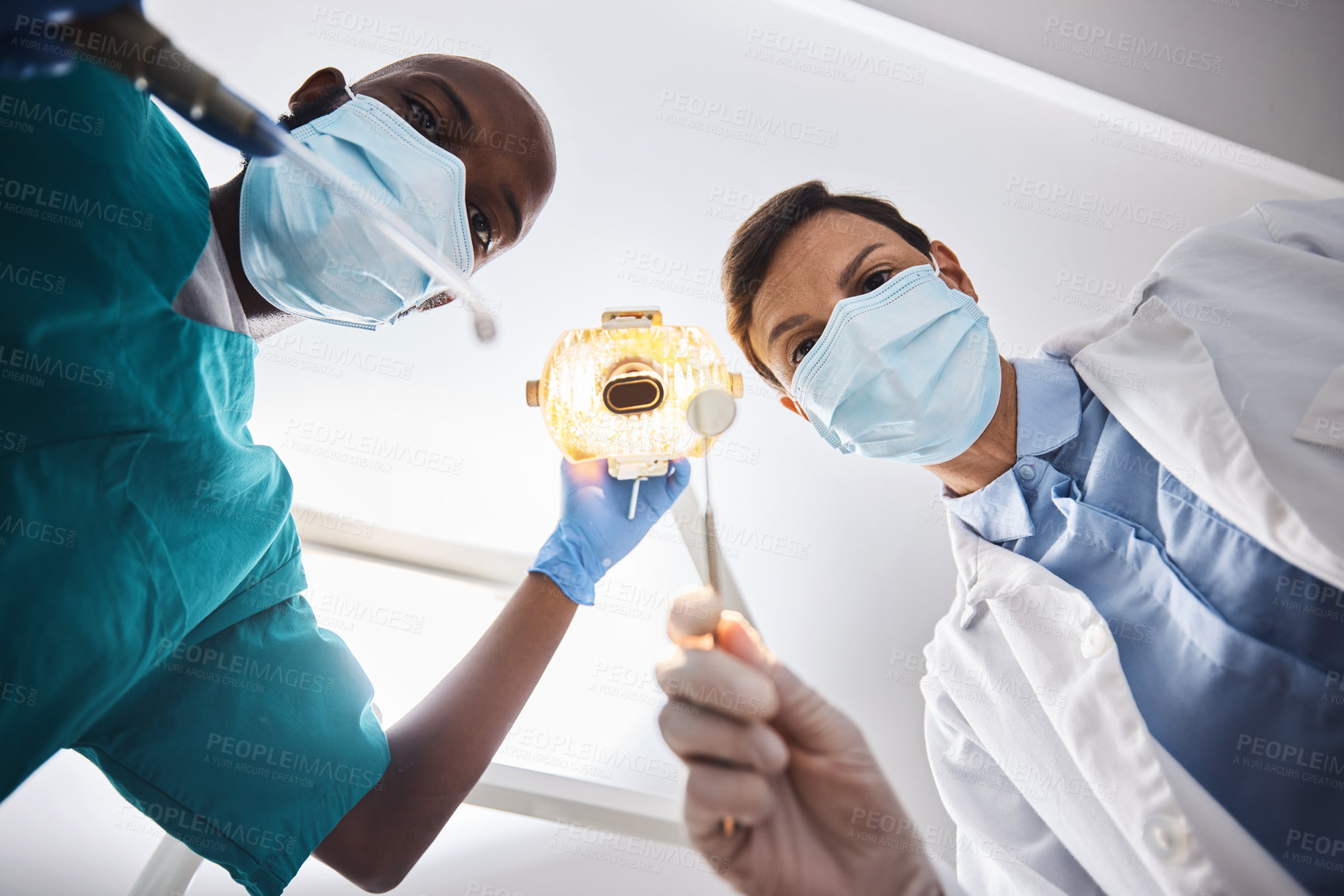 Buy stock photo Low angle shot of two dentists getting ready to perform a procedure on a patient