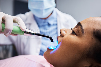 Buy stock photo Shot of a dentist using a curing light on a patient during orthodontic treatment