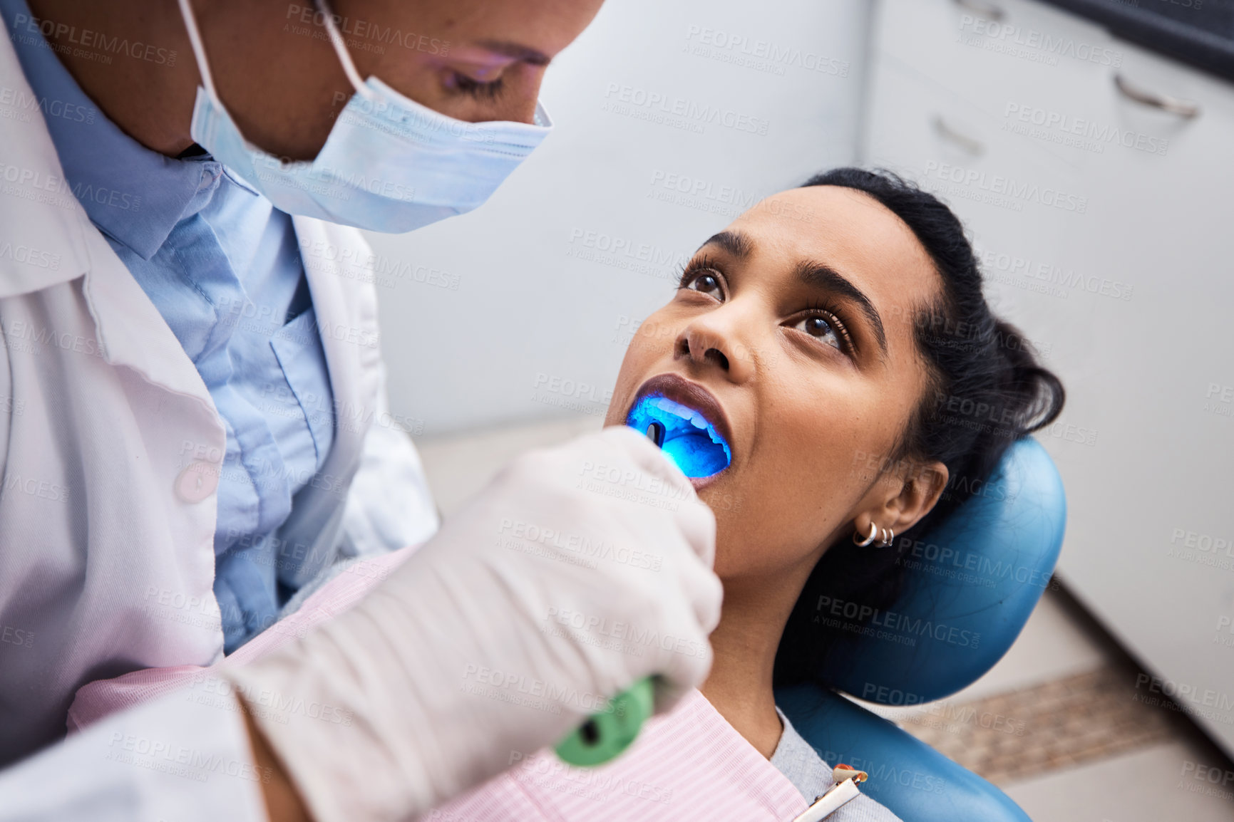 Buy stock photo Shot of a dentist using a curing light on a patient during orthodontic treatment