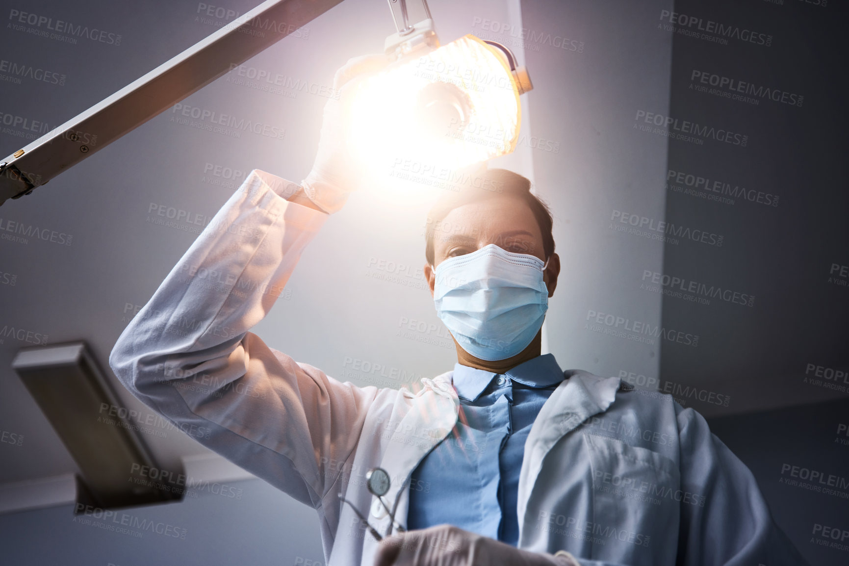 Buy stock photo Low angle shot of a dentist getting ready to perform a procedure on a patient