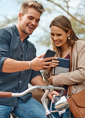 Buy stock photo Shot of two young students using a mobile phone outside on campus