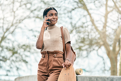 Buy stock photo Shot of an attractive young student using her mobile phone while holding a skateboard on campus