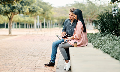 Buy stock photo Shot of two young  students using a laptop while sitting outside on campus