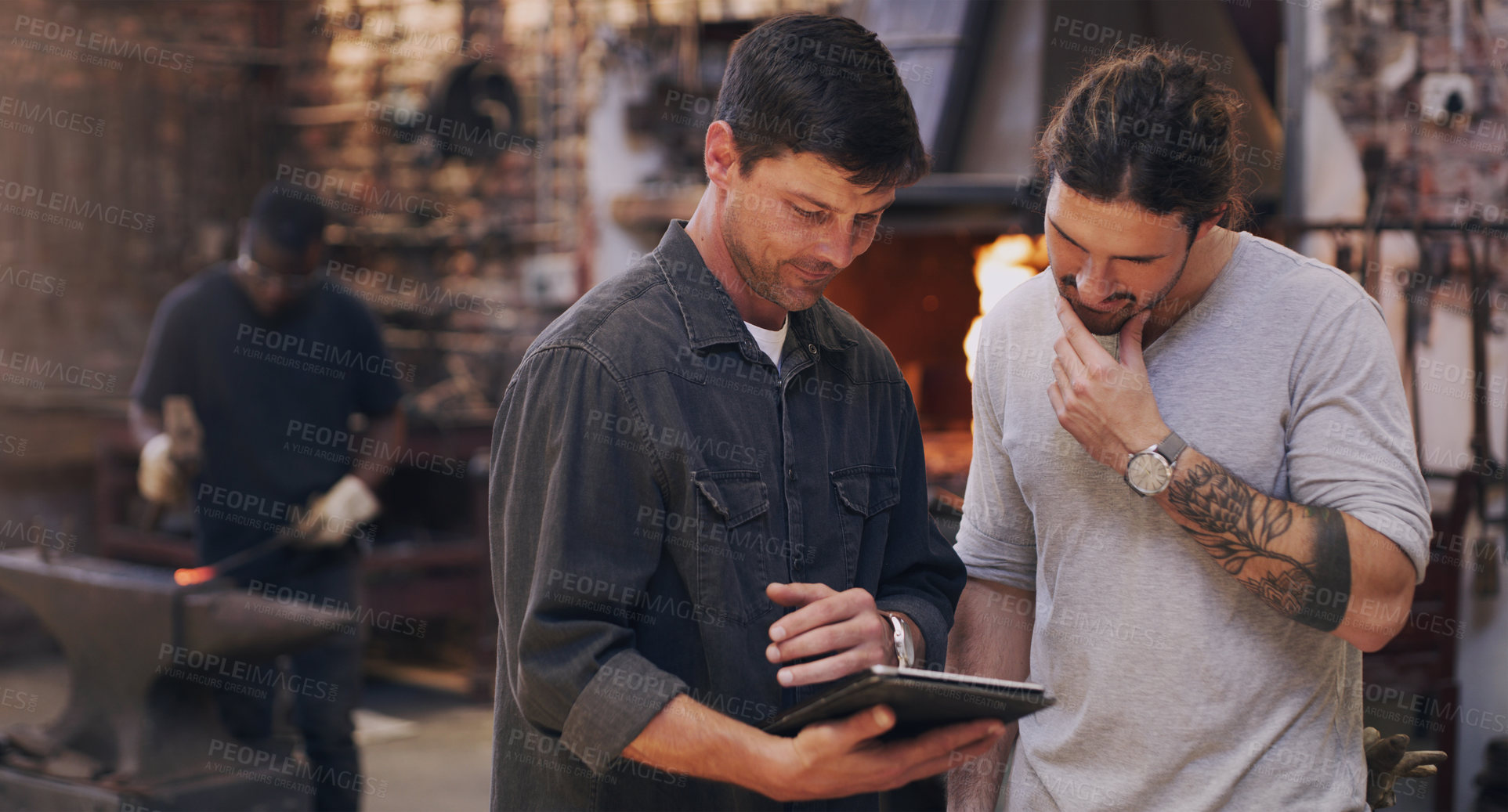 Buy stock photo Shot of two men discussing something on a digital tablet while in their workshop