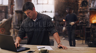 Buy stock photo Workshop, man and working on laptop in metal blacksmith factory for trade business, finance and industry technology. Welder, computer and online paperwork for businessman, staff and forge worker