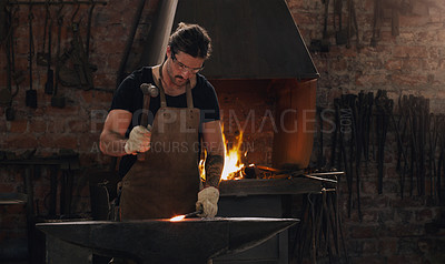 Buy stock photo Hammer, anvil and fire with a man working in a foundry for metal work manufacturing or production. Industry, welding and trade with a young male blacksmith in a workshop, plant or industrial forge