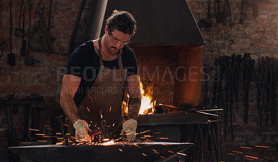 Buy stock photo Hammer, anvil and fire with a man working in a forge for metal work manufacturing or production. Industry, welding and trade with a male blacksmith at work in a factory, plant or industrial workshop