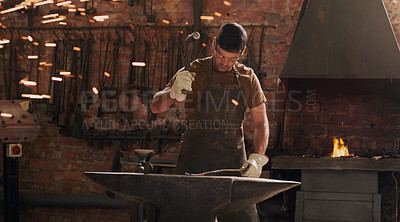 Buy stock photo Shot of a metal worker hitting a hot metal rod with a hammer in a welding workshop