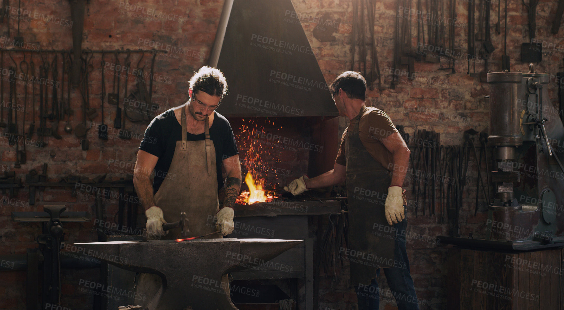 Buy stock photo Hammer, anvil and fire with men working in a foundry for metal work manufacturing or production. Industry, welding and trade with blacksmith craftsmen in a steel workshop, plant or industrial forge