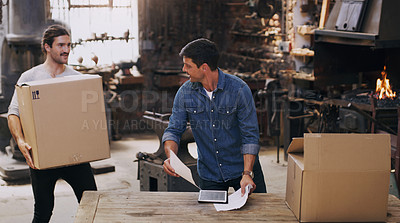 Buy stock photo Shot of two men sorting orders and deliveries while working together in a workshop