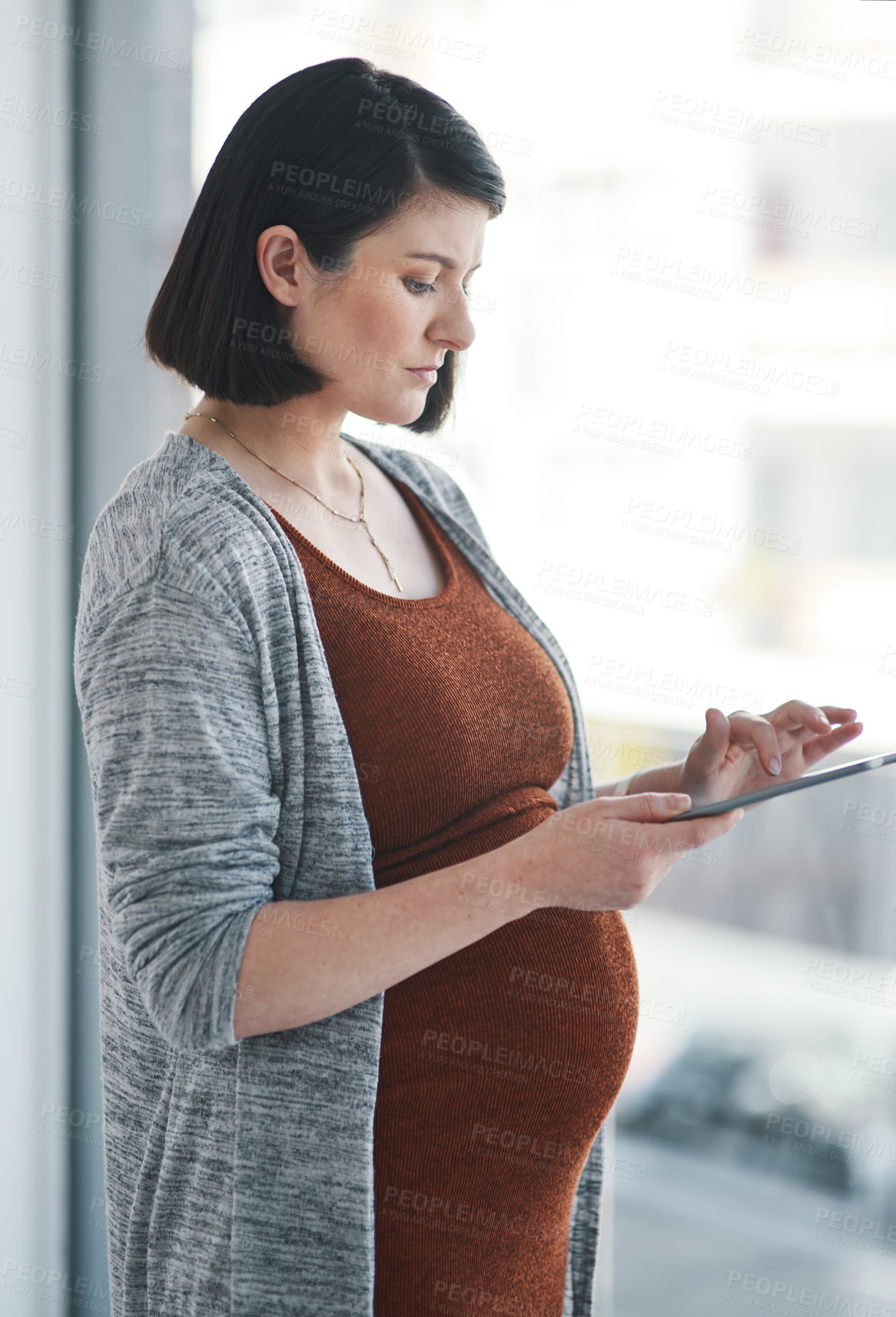 Buy stock photo Shot of a pregnant young businesswoman using a digital tablet in a modern office