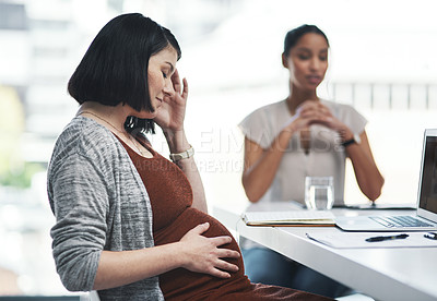 Buy stock photo Shot of a pregnant young businesswoman feeling stressed during a team meeting in a modern office