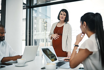 Buy stock photo Shot of a pregnant young businesswoman leading a team meeting in a modern office