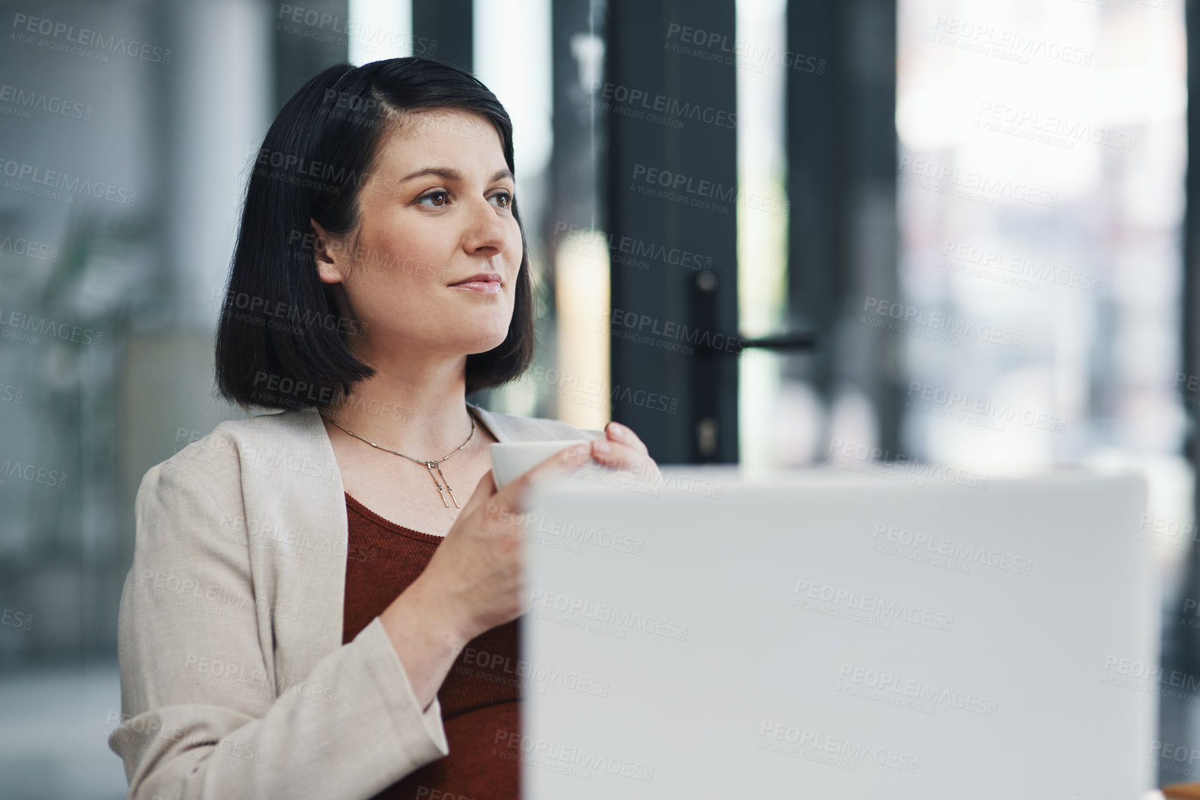 Buy stock photo Shot of a pregnant young businesswoman having coffee and using a laptop in a modern office