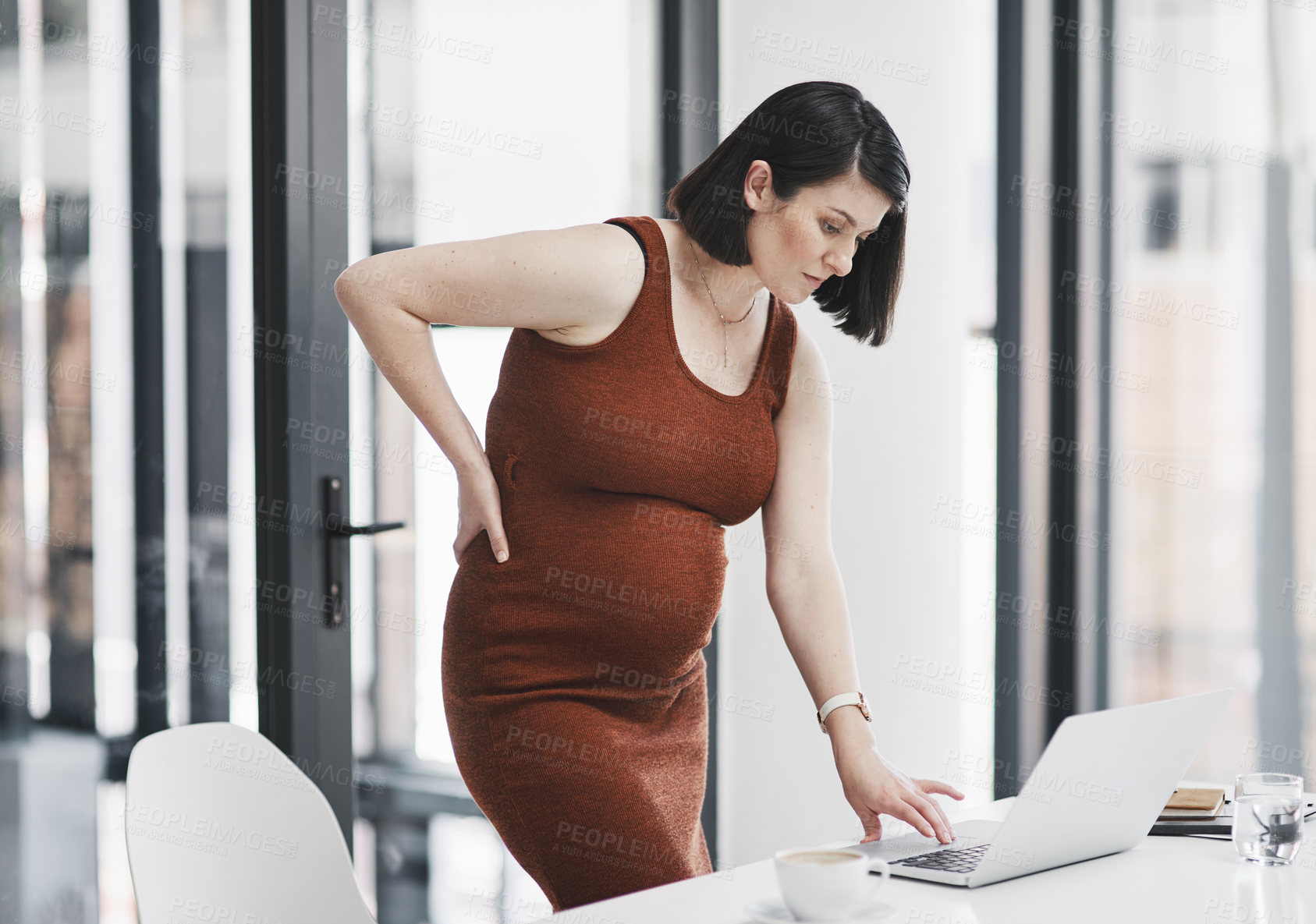 Buy stock photo Shot of of a pregnant young businesswoman feeling unwell while working in a modern office