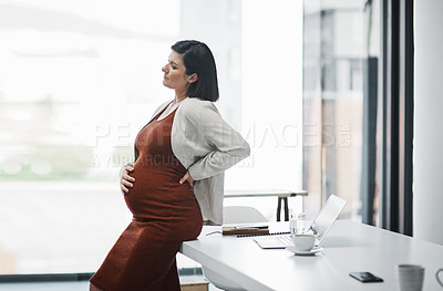 Buy stock photo Shot of a pregnant young businesswoman feeling unwell while working in a modern office