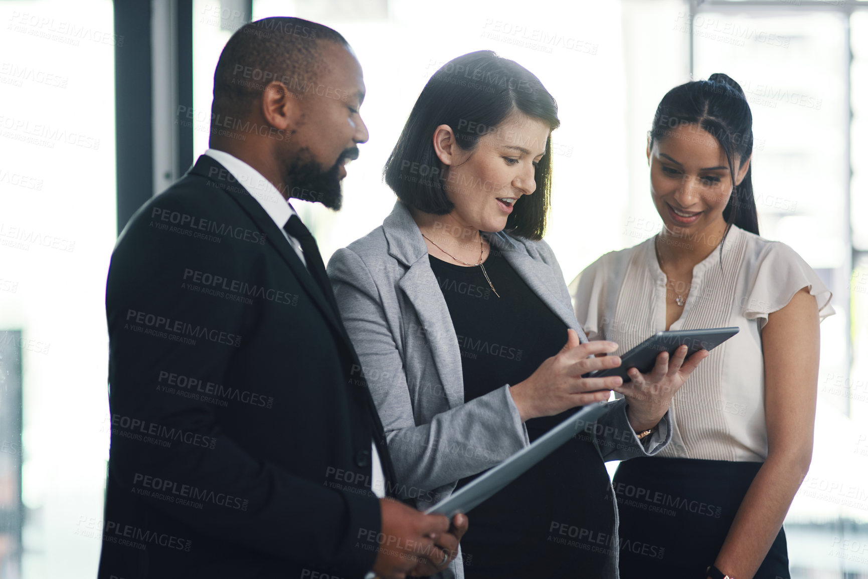 Buy stock photo Shot of a group of businesspeople using a digital tablet during a meeting in a modern office