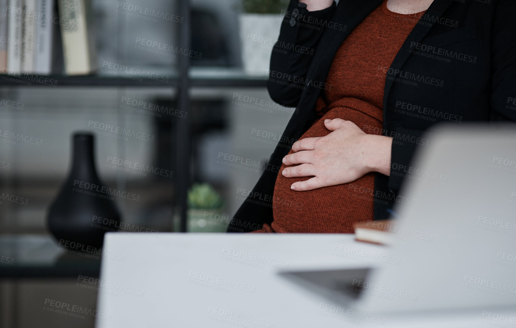 Buy stock photo Cropped shot of an unrecognizable businesswoman sitting alone in the office and holding her pregnant stomach
