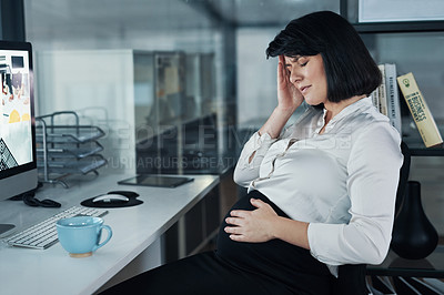 Buy stock photo Cropped shot of an attractive businesswoman sitting and feeling stressed while holding her pregnant tummy in the office