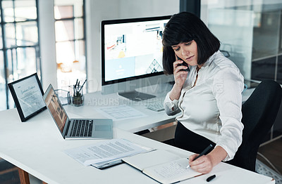 Buy stock photo Cropped shot of a pregnant businesswoman sitting alone in her office and using her cellphone while writing notes