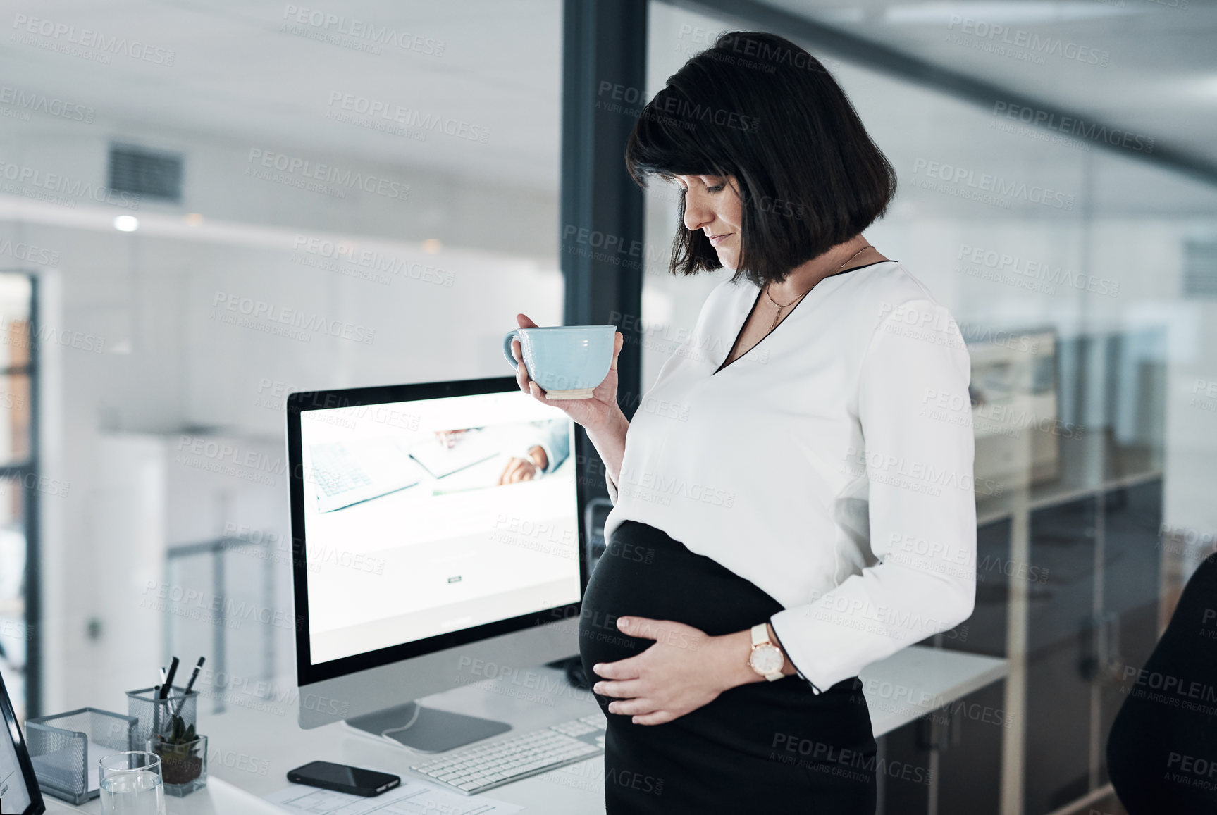 Buy stock photo Cropped shot of an attractive pregnant businesswoman standing alone in the office and having a cup of tea